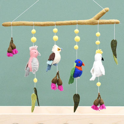 Colorful bird-themed mobile with hanging toys on a branch against a light blue background