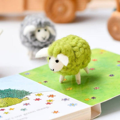 Green sheep toy on a book with a blurred background