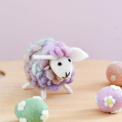Small felted sheep toy with pastel colors on a wooden surface
