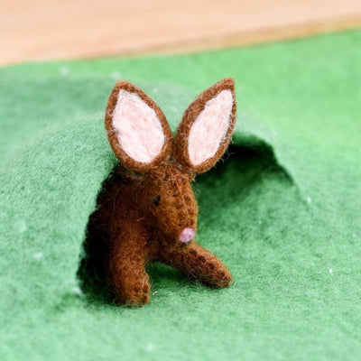 Small brown felt bunny toy on a green surface