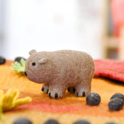 Small toy wombat figure on a textured surface with blurred background