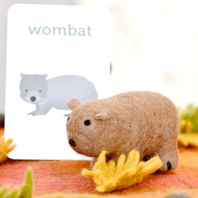 Toy wombat next to a card with an illustration of a wombat on a colorful background
