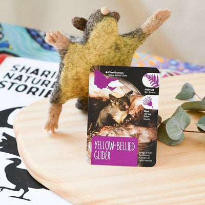 Yellow-bellied glider toy with educational card on a wooden surface