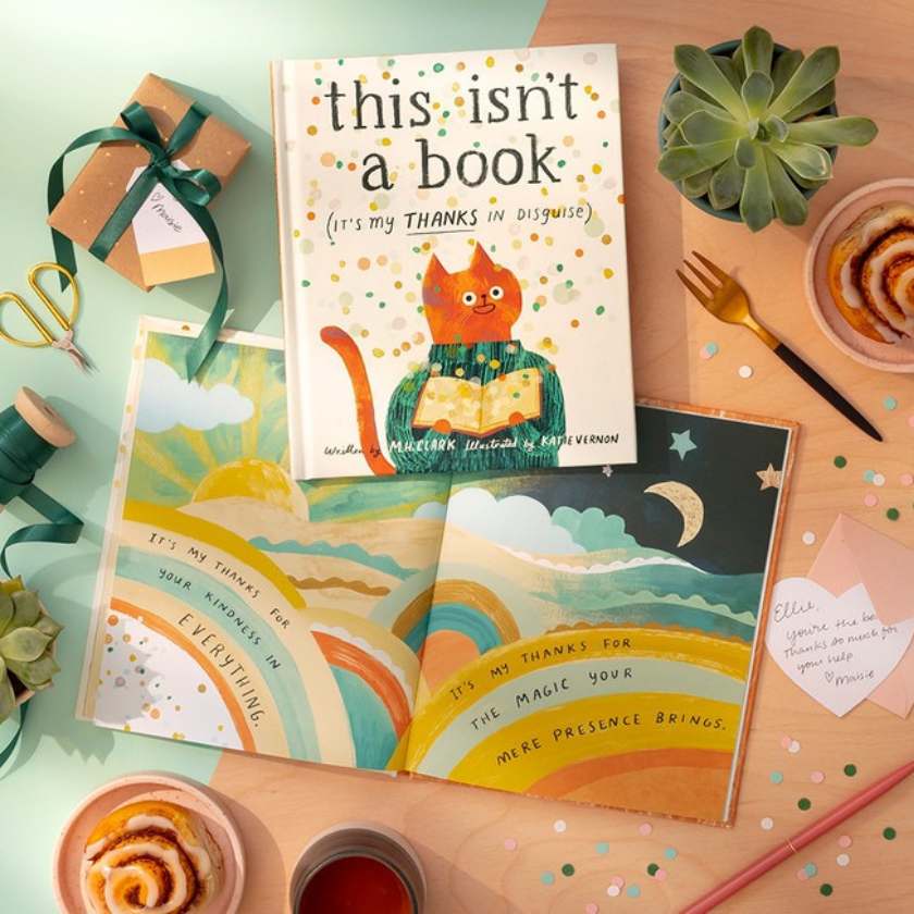 Children's book titled 'this isn't a book (it's my THANKS in disguise)' on a table with decorative items.