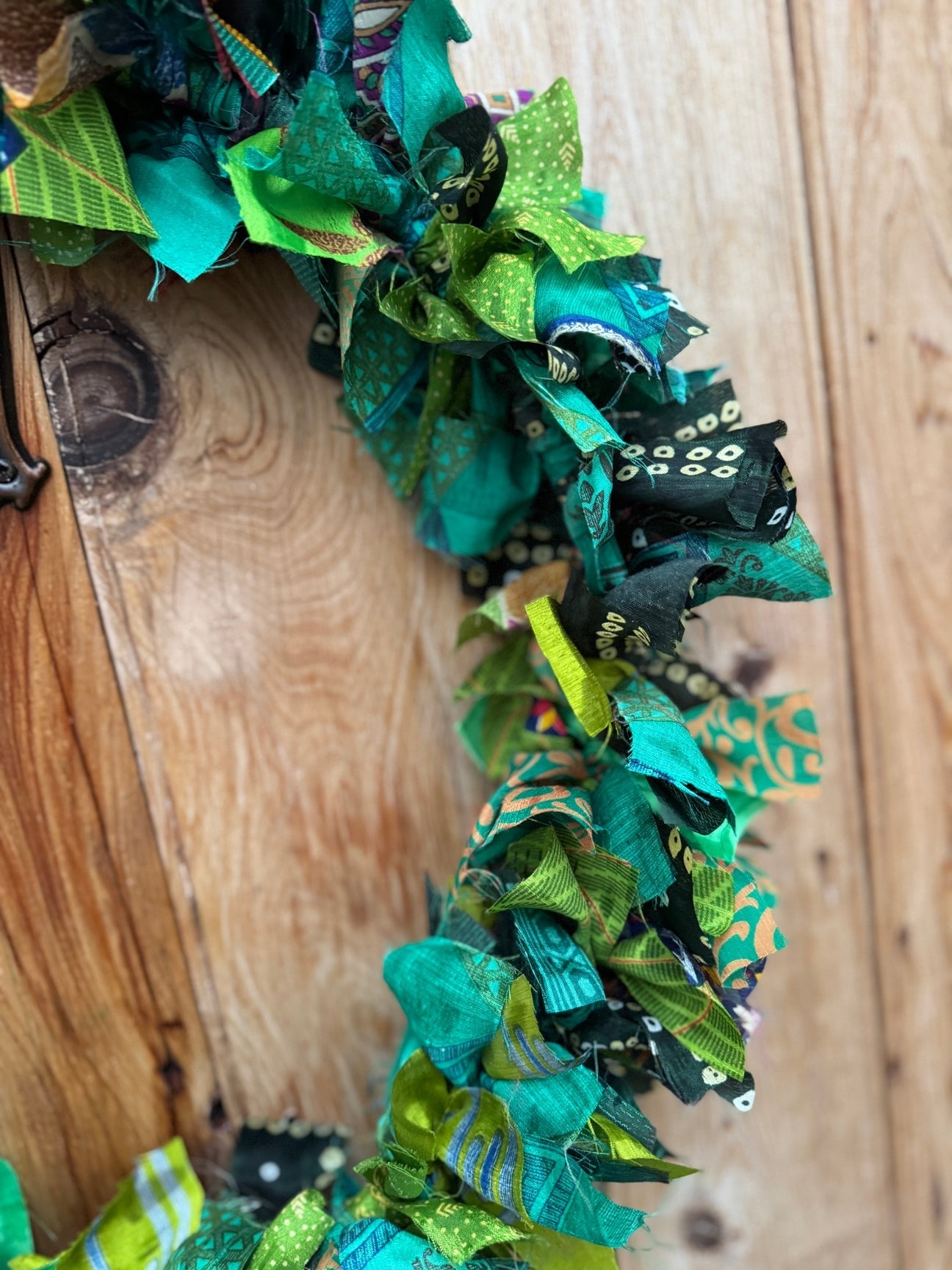 Decorative wreath with green and black ribbons on a wooden surface