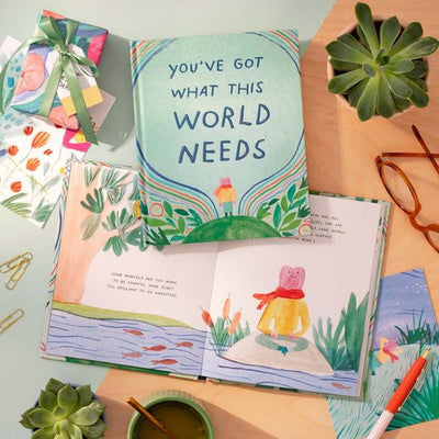 Open book with illustrations and a motivational quote on a desk with stationery items.