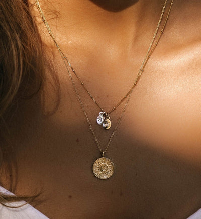 A Initial Charm layered on a gold necklace