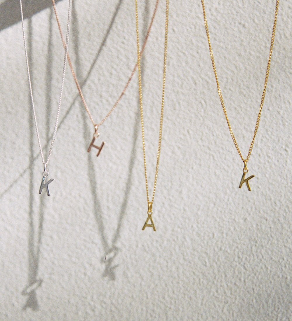 Kirstin Ash Initial Charms on necklaces hanging in the air