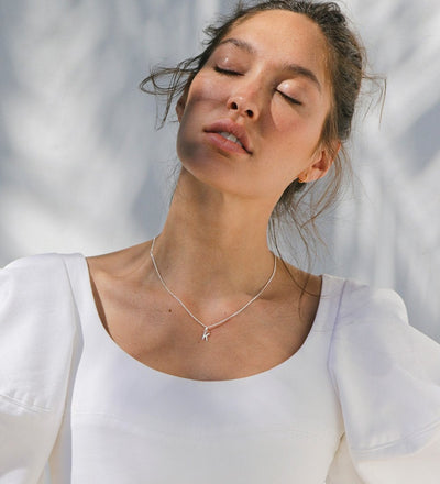 Model wearing K initial charm on a silver necklace